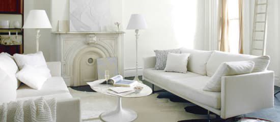 A living room with white furniture and a fireplace.